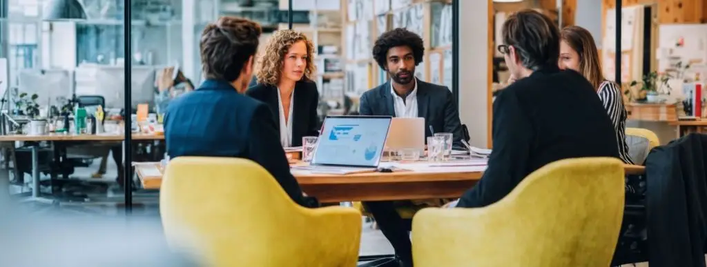 A diverse leadership team collaborating around a table in a modern workplace, representing neurodiversity consultancy and inclusive organisational strategy.