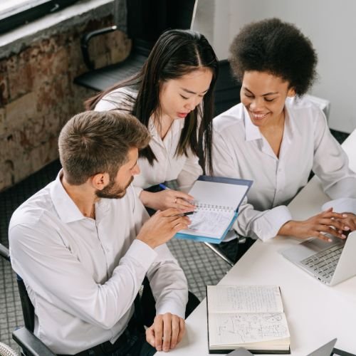 HR team members reviewing notes and collaborating on workplace policies at a desk.