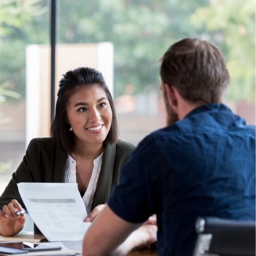 A manager having a supportive one-to-one conversation with a colleague during a workplace meeting.