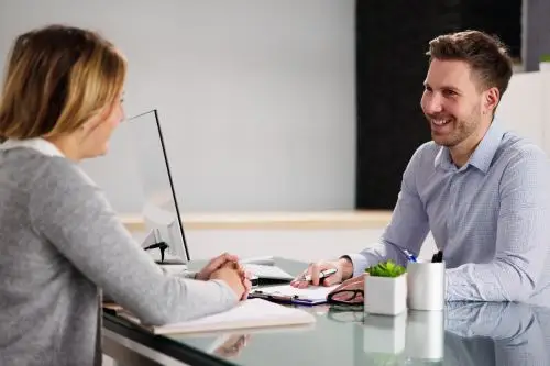 One-to-one workplace needs assessment conversation between an assessor and an employee in a professional setting.